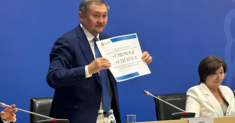 Таратуға көмектесіңіз министр үкіметке байланыс нөмірлері жазылған плакатты алып келді